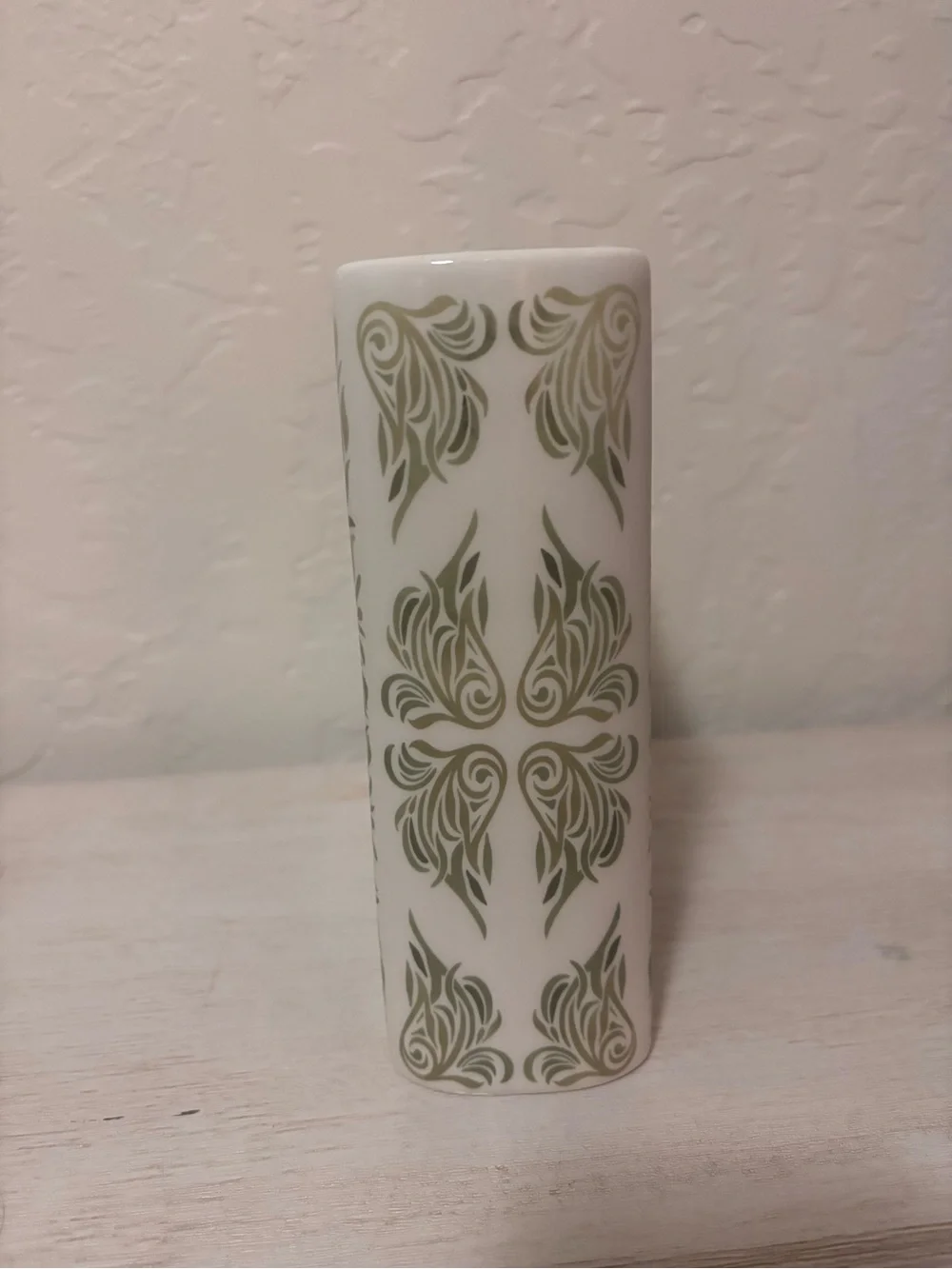 ceramic book vase with green floral swirls and the words…
